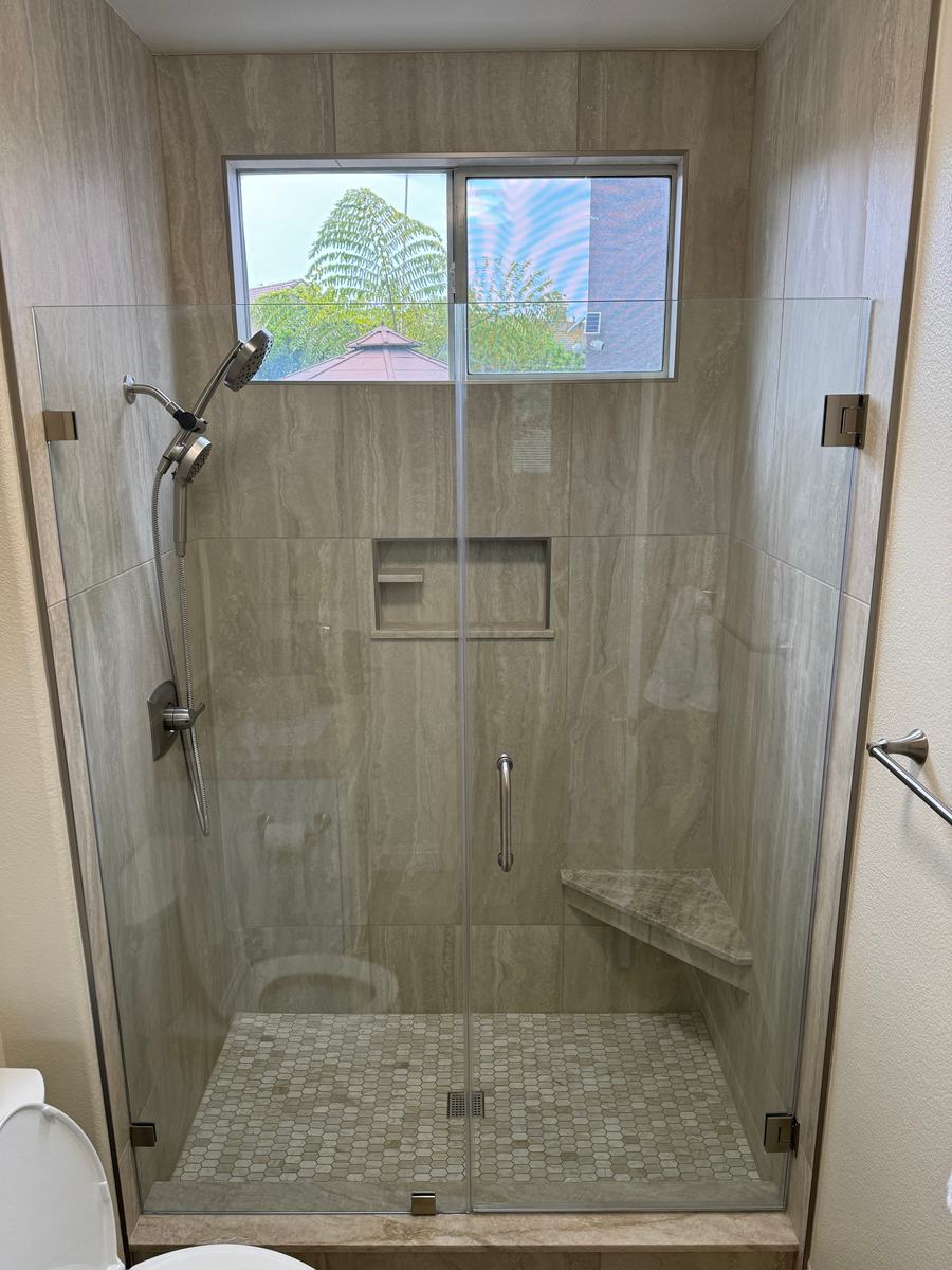 Bathroom installation detail with stone surfaces and a framed shower opening.